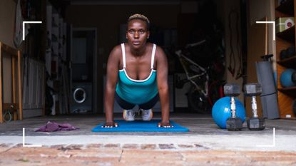 Woman wearing running kit doing a plank in garage at home, representing strength training for runners