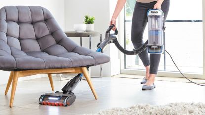 A Shark corded vacuum cleaner being used in a living room